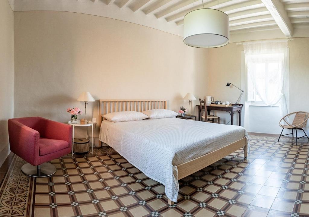 a bedroom with a bed and a red chair at La Dimora di Corte a Lucca in Lucca