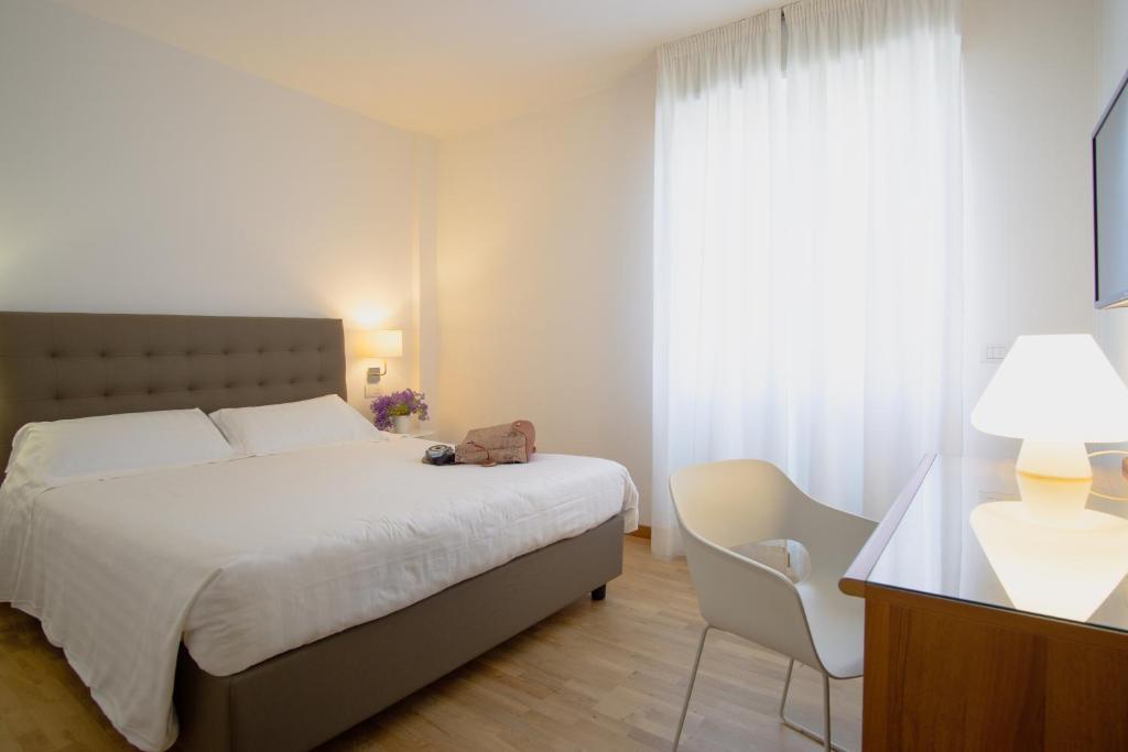 a bedroom with a bed and a desk and a window at Mistral2 Hotel in Oristano