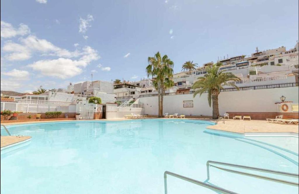 ein großer Pool mit Palmen und Gebäuden in der Unterkunft Casa lele en anfi del mar in Los Caideros