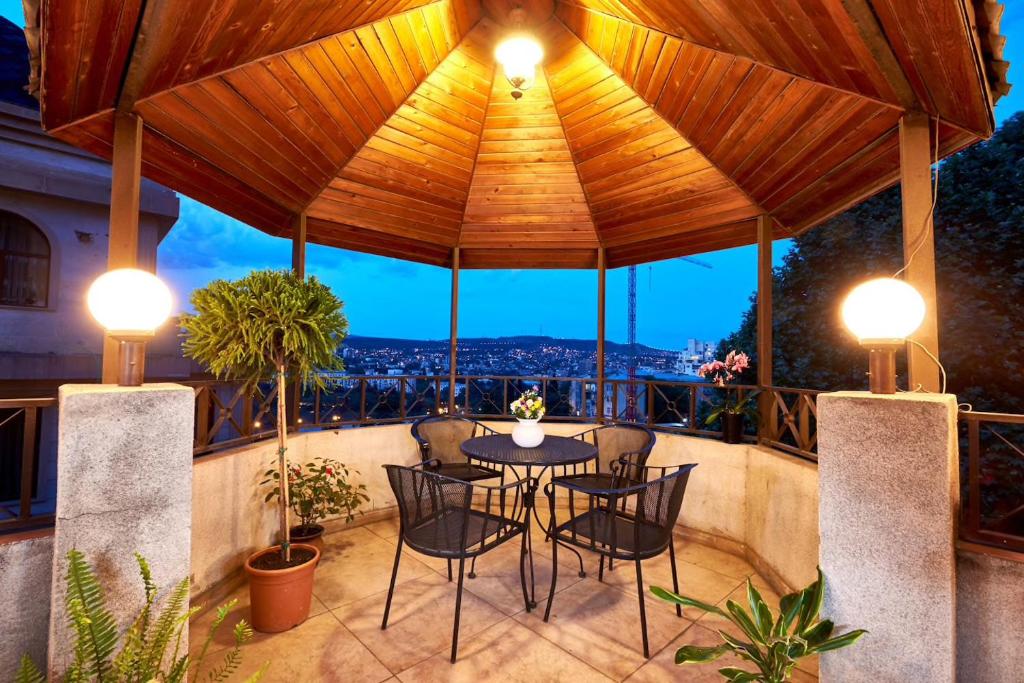 un patio con mesa, sillas y luces en Iliani Hotel, en Tiflis