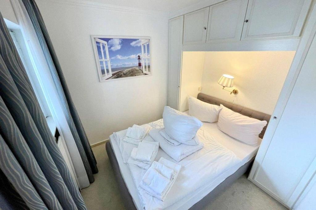 ein kleines Schlafzimmer mit einem Bett mit weißer Bettwäsche und Kissen in der Unterkunft App. 15 in Westerland