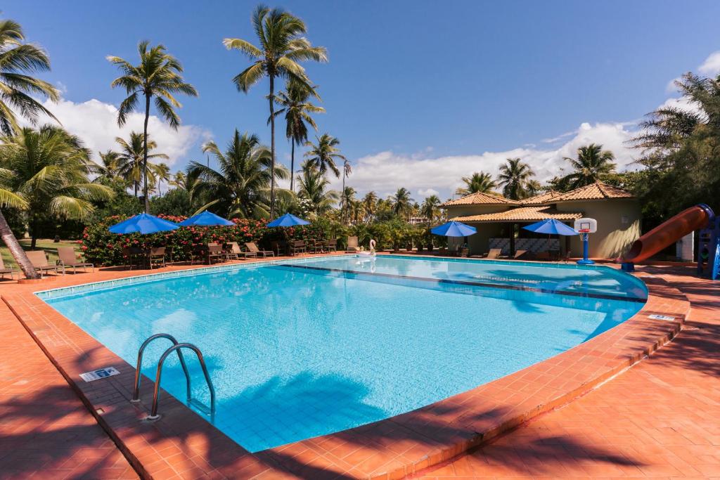 una piscina en un complejo con palmeras en Resort Costa Dos Coqueiros, en Imbassai