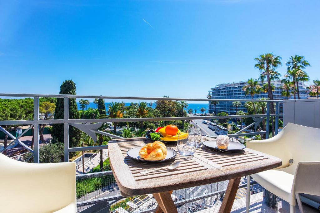 une table avec de la nourriture sur un balcon avec vue sur l'océan dans l'établissement PALAIS ALBERT 1ER AP4292 By Riviera Holiday Homes, à Nice