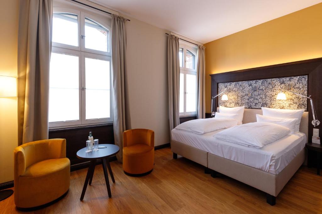 a bedroom with a bed and a table and two chairs at Hotel Alte Post in Konstanz