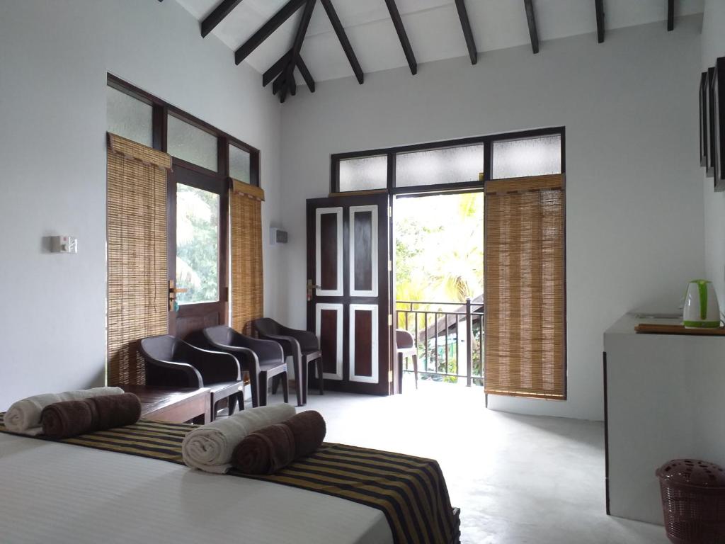 a bedroom with a bed and chairs and windows at Green Wood Villa Negombo in Negombo