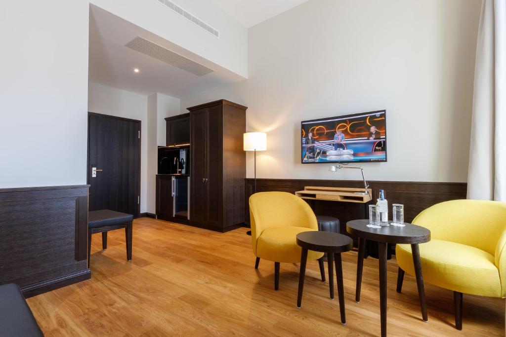 a living room with yellow chairs and a table at Hotel Alte Post in Konstanz