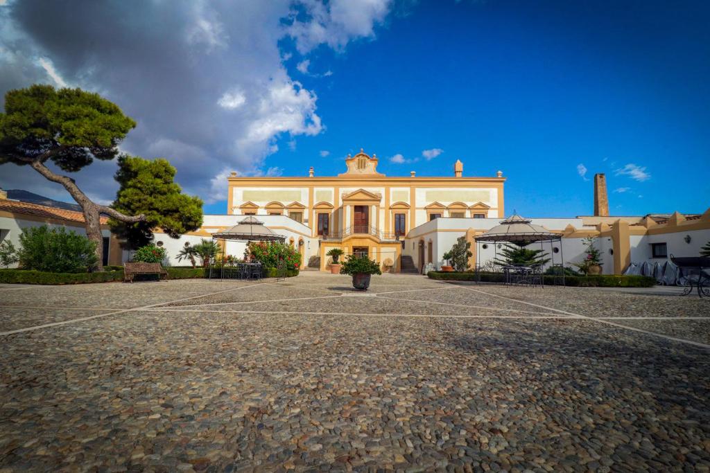 un grand bâtiment blanc avec un arbre en face dans l'établissement Villa del Gattopardo, à Palerme