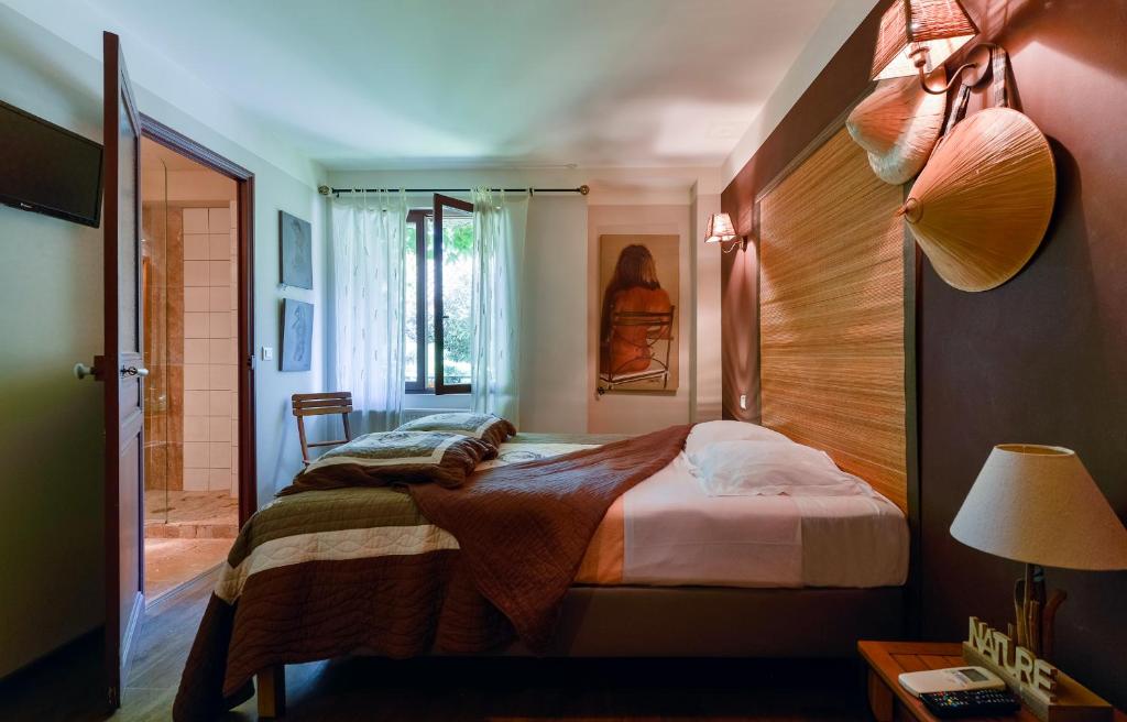 um quarto com uma cama e uma cabeceira em madeira em Hôtel Mas Vidau Porte des Alpilles em Saint-Étienne-du-Grès