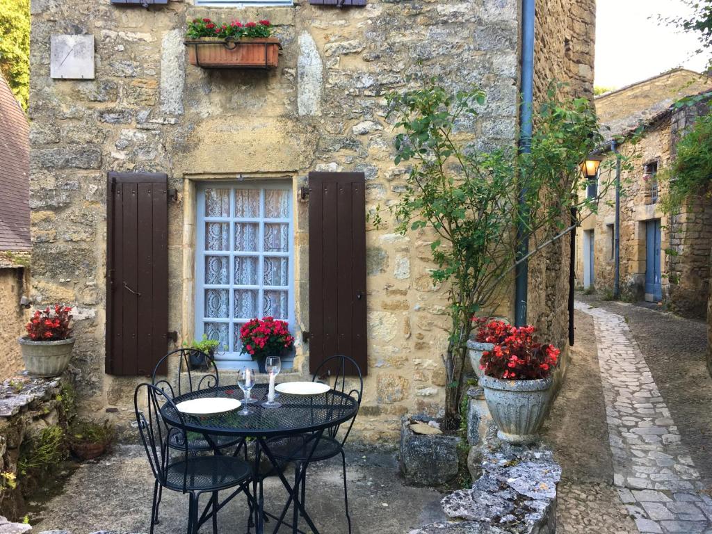 a table and chairs in front of a building at La Petite Maison in Beynac-et-Cazenac