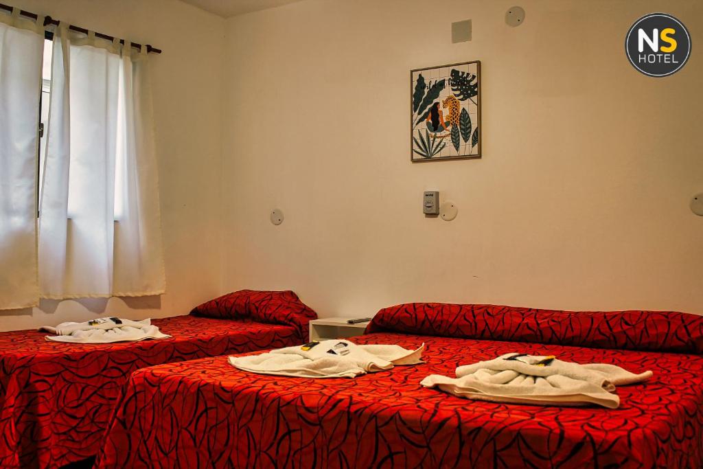 2 Betten in einem Zimmer mit roter Bettwäsche in der Unterkunft Ns Hotel in Termas de Río Hondo