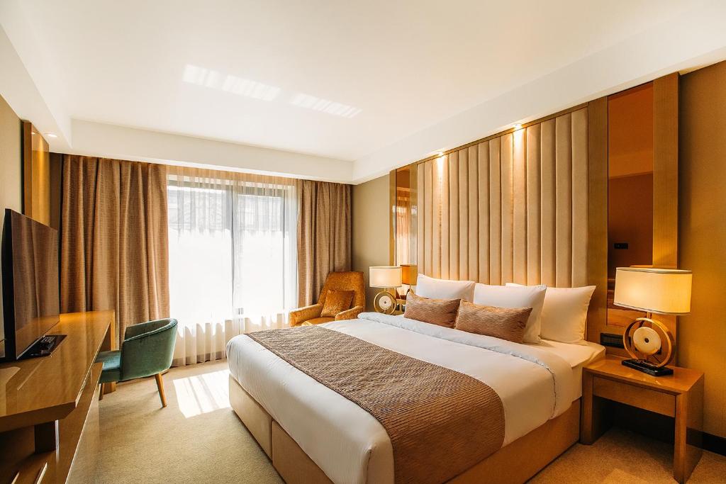 Marjan Plaza Hotel في تبليسي: غرفه فندقيه سرير كبير وتلفزيون