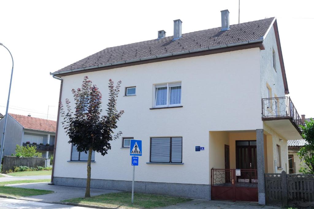 une maison blanche avec un arbre en face dans l'établissement Apartman Noa 16, à Ðurđevac