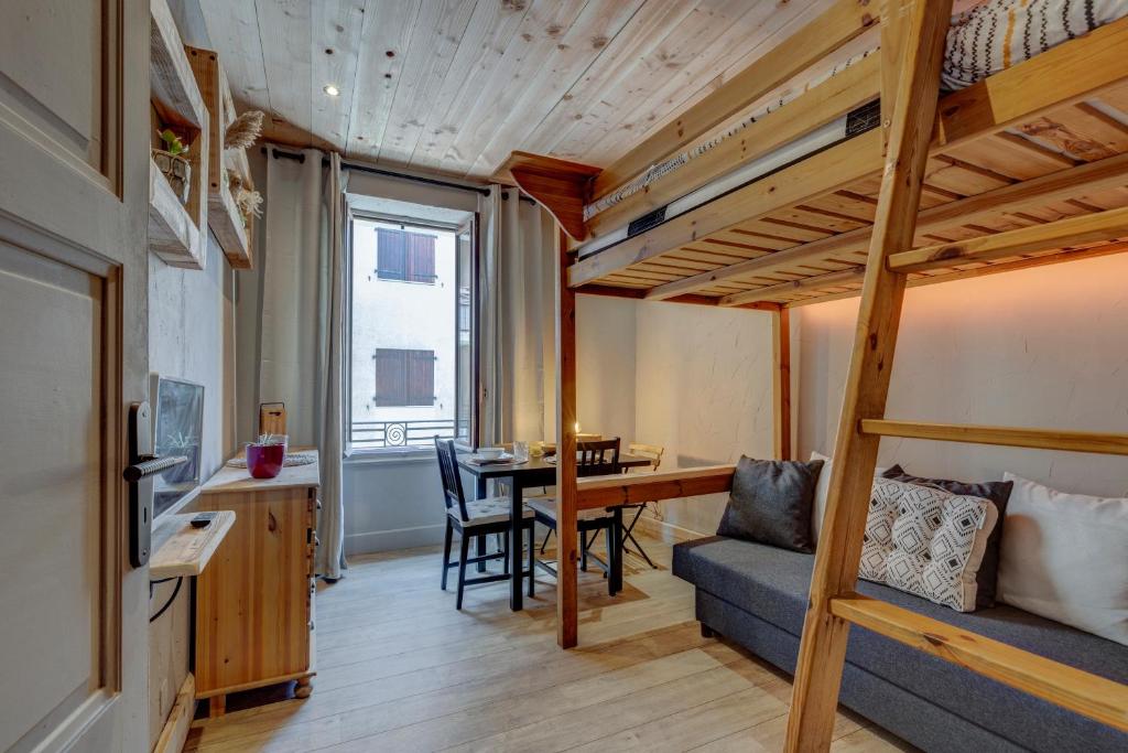 Habitación con cama elevada y mesa de comedor. en Les Trois M, en Aime La Plagne