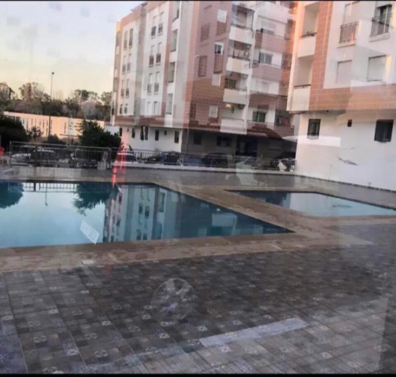een leeg zwembad voor een gebouw bij 2 slaapkamers appartement zwembad in Tanger