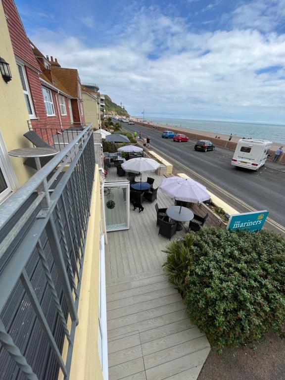 un balcón con mesas y sombrillas junto al océano en Mariners Hotel, en Seaton