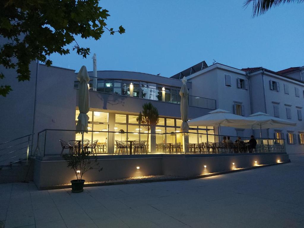 een gebouw met tafels en parasols ervoor bij Hotel Villa Elisabeth - Veli Lošinj Health Resort in Veli Lošinj