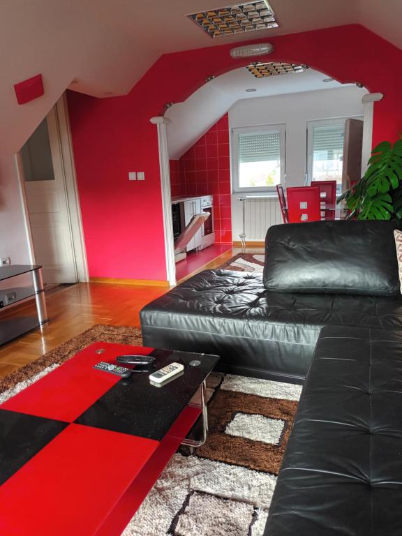 sala de estar con sofá de cuero negro y paredes rojas en Sve u jednom en Bijelo Polje