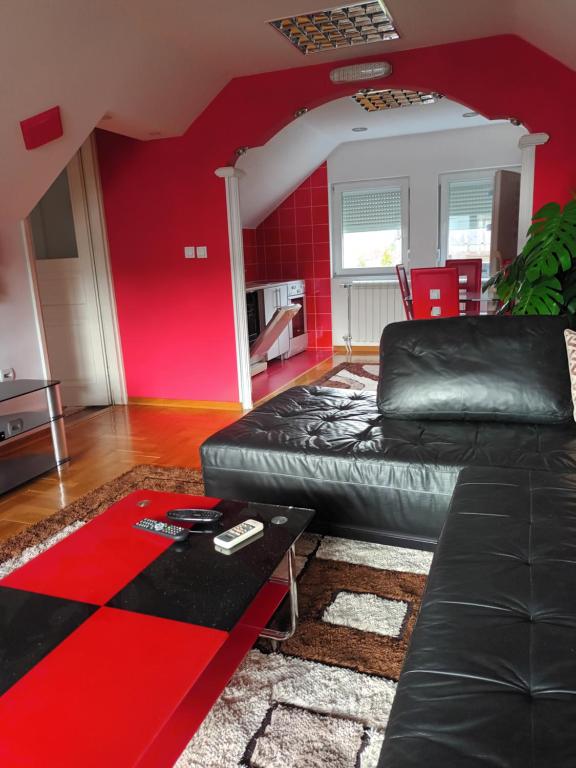 a living room with a black leather couch and red walls at Sve u jednom in Bijelo Polje