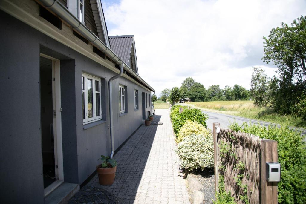 ein Haus mit einem gemauerten Bürgersteig neben einer Straße in der Unterkunft Værelse, spiseområde, tv-stue og eget bad på landet in Kværndrup