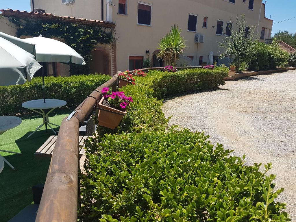 un jardín con flores, una mesa y una sombrilla en For Two Monolocali en Marina di Camerota