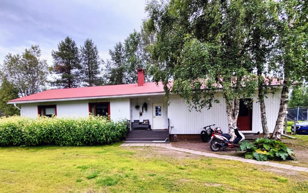 una casa blanca con techo rojo y una motocicleta aparcada delante en Holiday House Mäntyniemi en Hossa