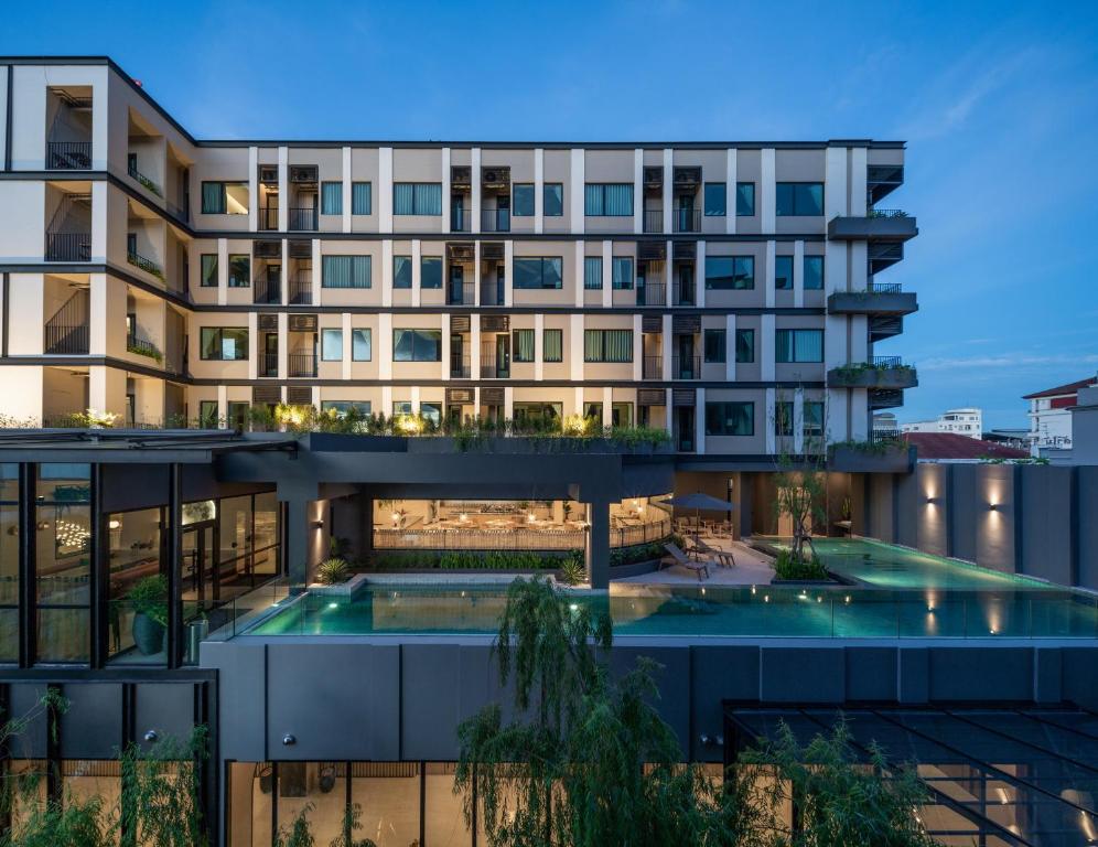 an apartment building with a swimming pool at dusk at Mii Hotel Srinakarin in Bangna