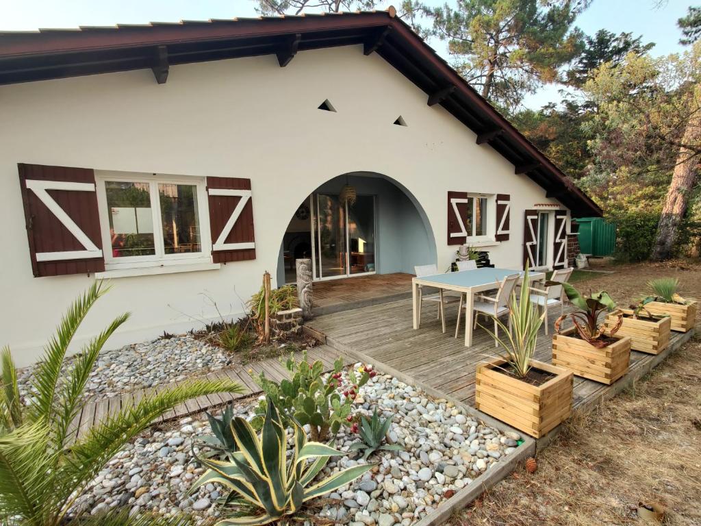 una casa con una terraza de madera frente a ella en maison landaise à proximité de la plage et centre en Biscarrosse-Plage