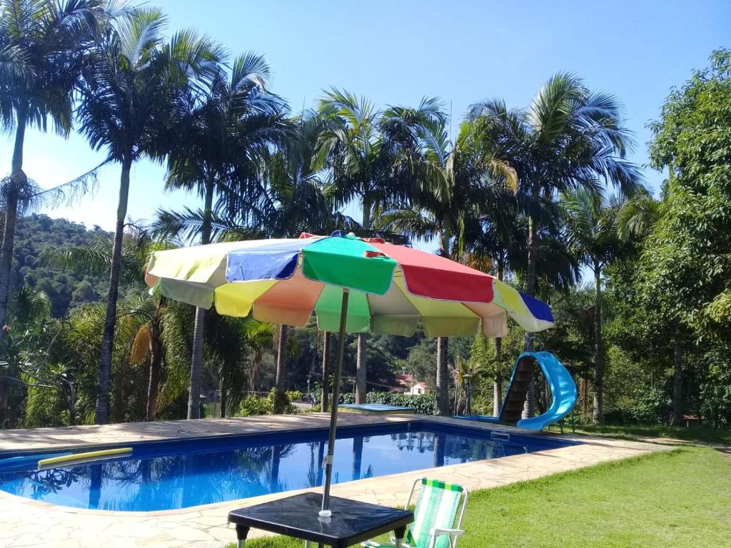 un ombrellone colorato seduto accanto alla piscina di CHACARA VALE DOS SONHOS LUGAR ENCANTADOR a Bom Jesus dos Perdões
