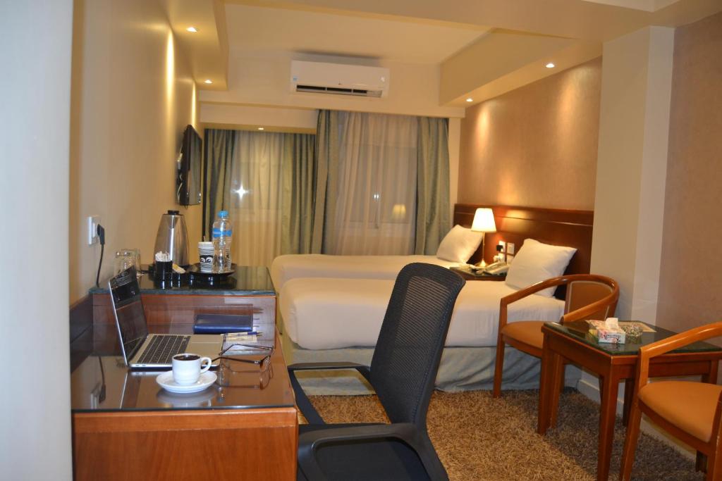 a hotel room with a bed and a desk with a laptop at Omar El Khayam Al Minya Hotel in Minya