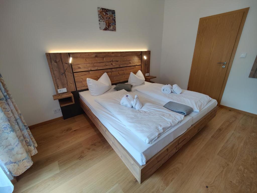 a bedroom with a large white bed with a wooden headboard at Ferien vom Ich, Bayerischer Wald, Hotel & Restaurant in Neukirchen