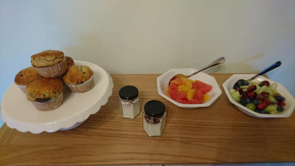 un tavolo con un piatto di muffin e un cesto di frutta di Rossclare Lodge a Enniskillen