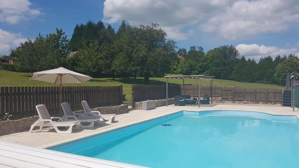 uma piscina com duas cadeiras e um guarda-sol em Character 2 bed cottage within walking distance of bar/restaurants em Piégut-Pluviers