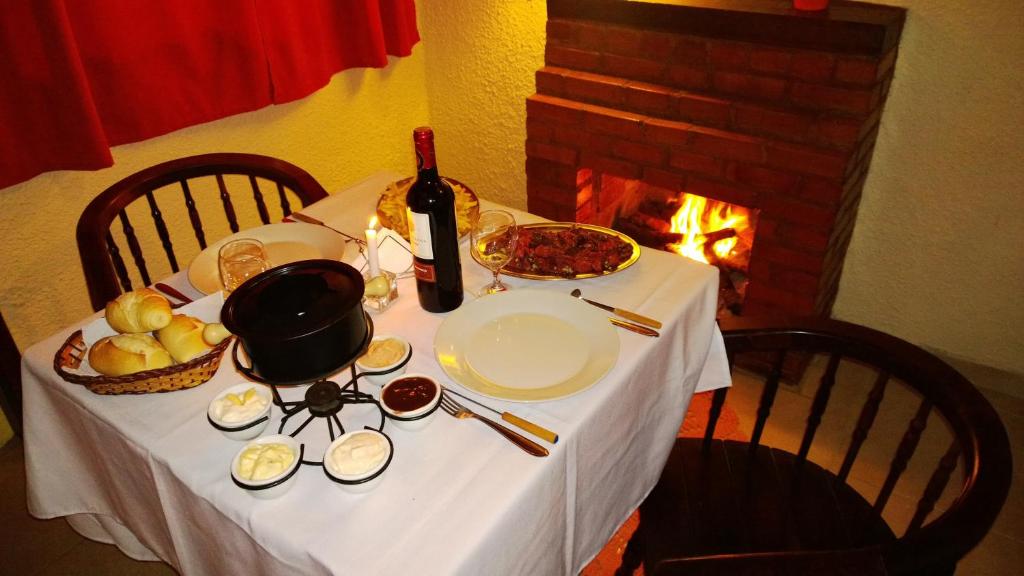 una mesa con mantel blanco y una botella de vino en Pousada Chale da Montanha, en Petrópolis