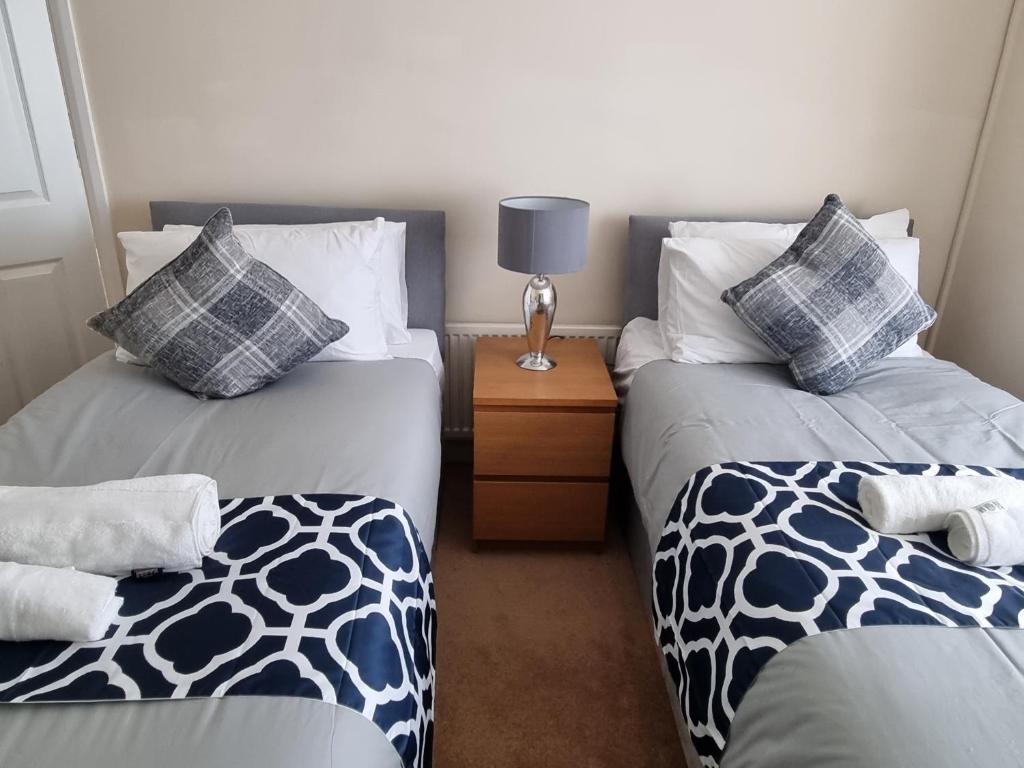 a room with two beds and a table with a lamp at Contractors Home from Home in South Benfleet