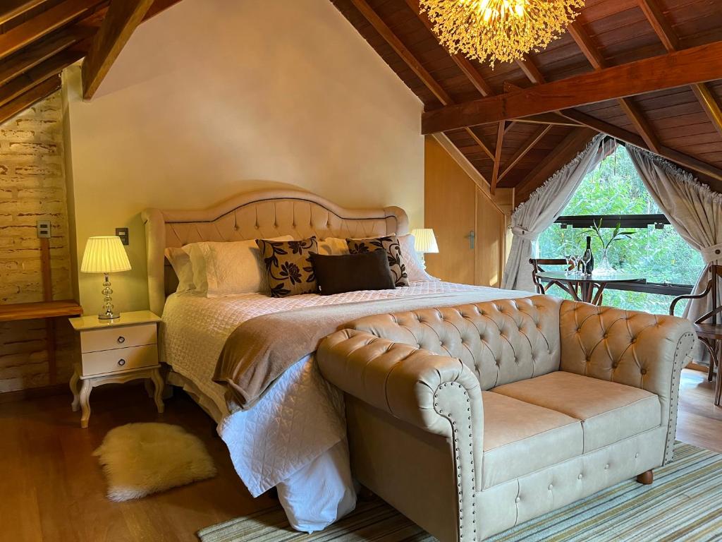 a bedroom with a bed with a couch and a chandelier at Pousada Dona Bendita in Monte Verde
