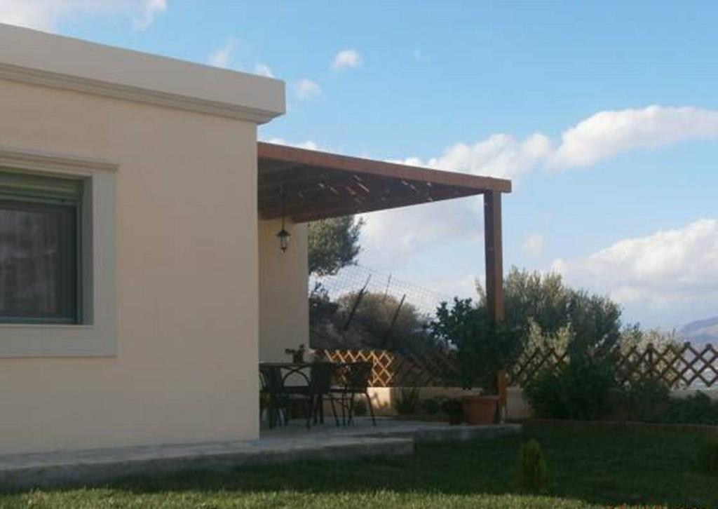 une terrasse couverte d'une maison avec une table et des chaises dans l'établissement Kyparissi, à Kamilárion