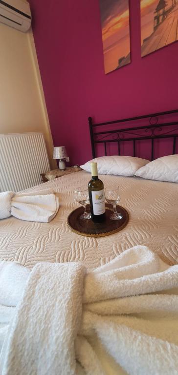 - Botella de vino y copas en la cama en panos rooms, en Kalambaka