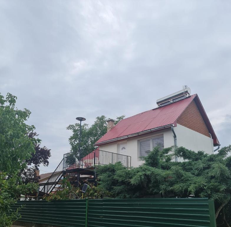 une maison avec un toit rouge et une clôture verte dans l'établissement Hobby Vendégház, à Kiskunmajsa