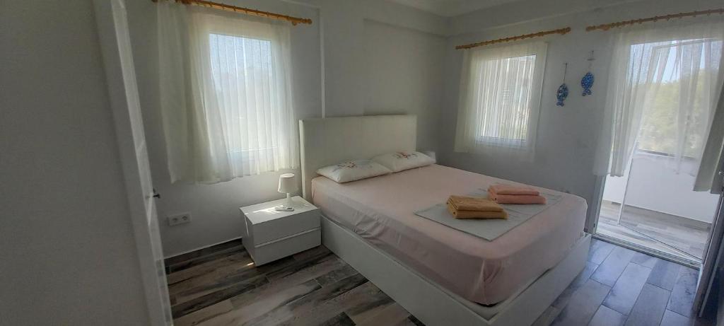 a white bedroom with a bed and a window at Rahat Ev in Bodrum City
