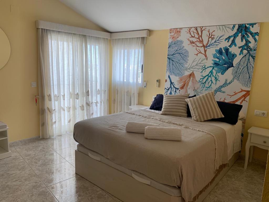 a bedroom with a large bed with a painting on the wall at Agradable Adosado 3 plantas Altea in Altea