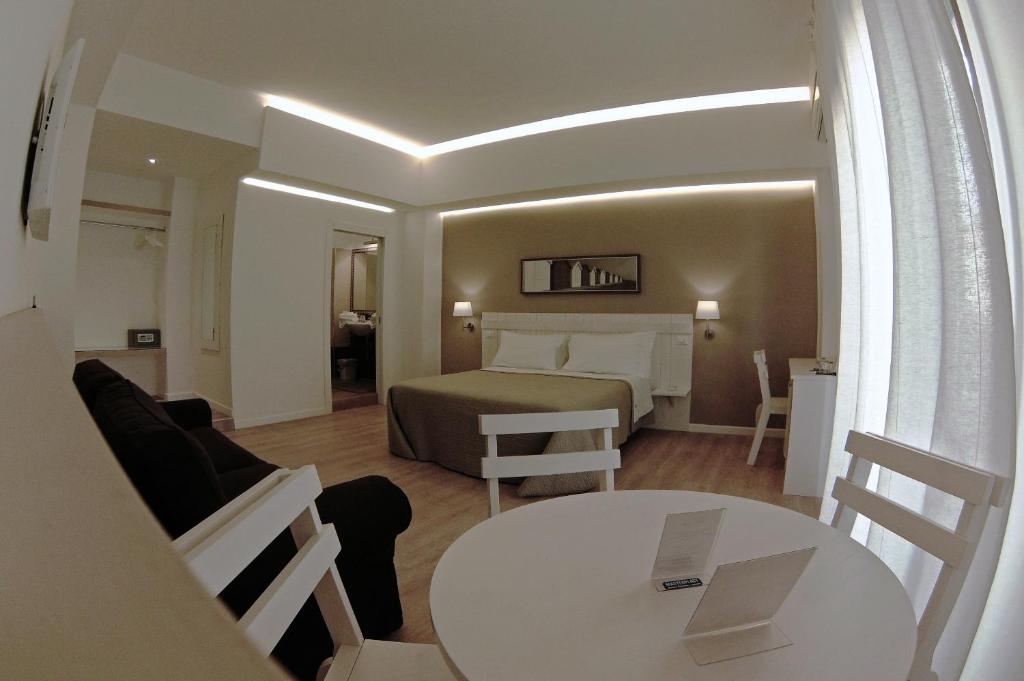 レッジョ・ディ・カラブリアにあるB&B Medinbluのベッド、テーブル、椅子が備わるホテルルームです。