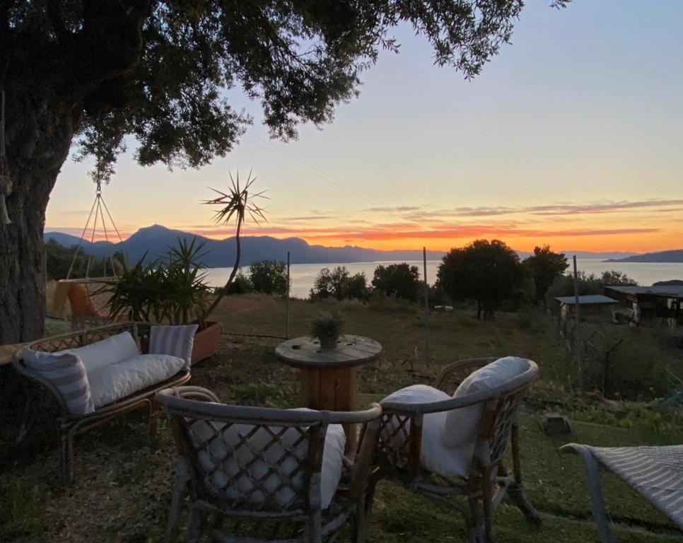a sunset from a patio with chairs and a table at Daphné Village House - close to Methana & Poros in Methana