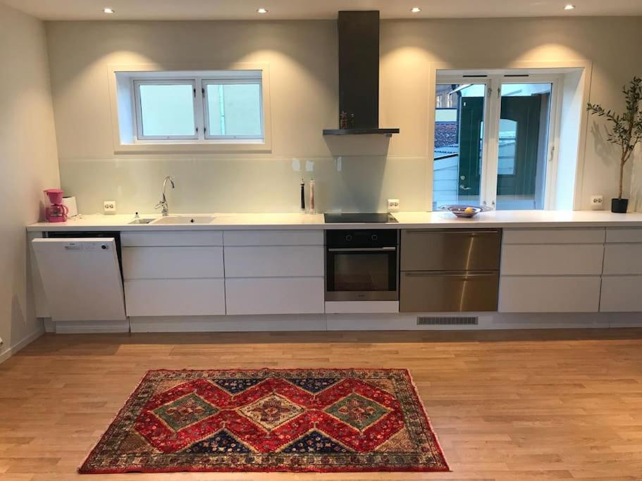 a kitchen with white cabinets and a rug on the floor at Stort hus i Porsgrunn sentrum med gangavstand til "alt" & gratis parkering til flere biler in Porsgrunn