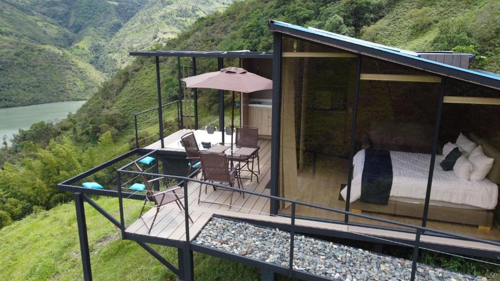 a house on a hill with a bed and a desk at Glamping Mirador del Guavio in Ubalá