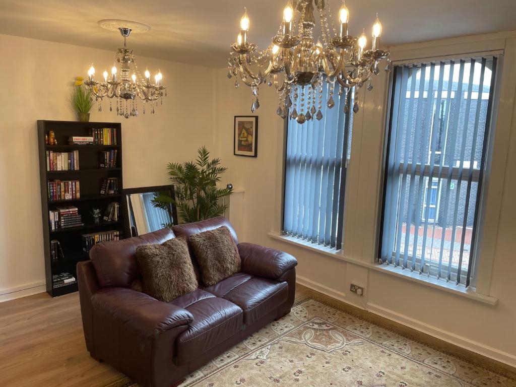 a living room with a leather couch and a chandelier at Lovely 2 bed Apartment, Arnold Town centre. in Nottingham