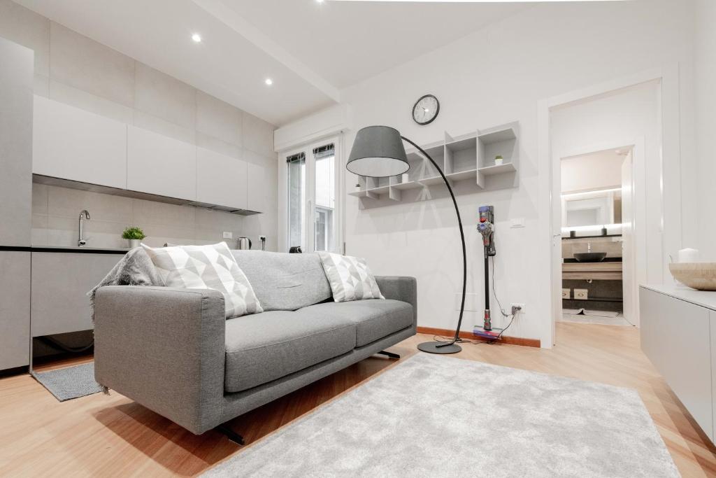 uma sala de estar com um sofá cinzento e uma cozinha em Realkasa Amendola Apartment em Bolonha