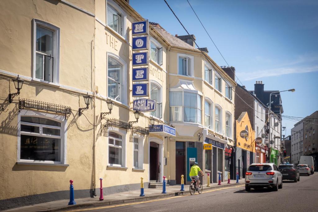 a man riding a bike down a street next to a building at Ashley Hotel in Cork