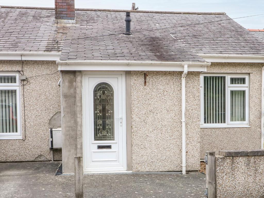 una casa con una puerta blanca y una ventana en 11 Bro Celyn, en Holyhead