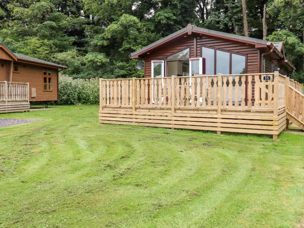 a wooden cabin with a deck and a house at Lodge 16 in Preston