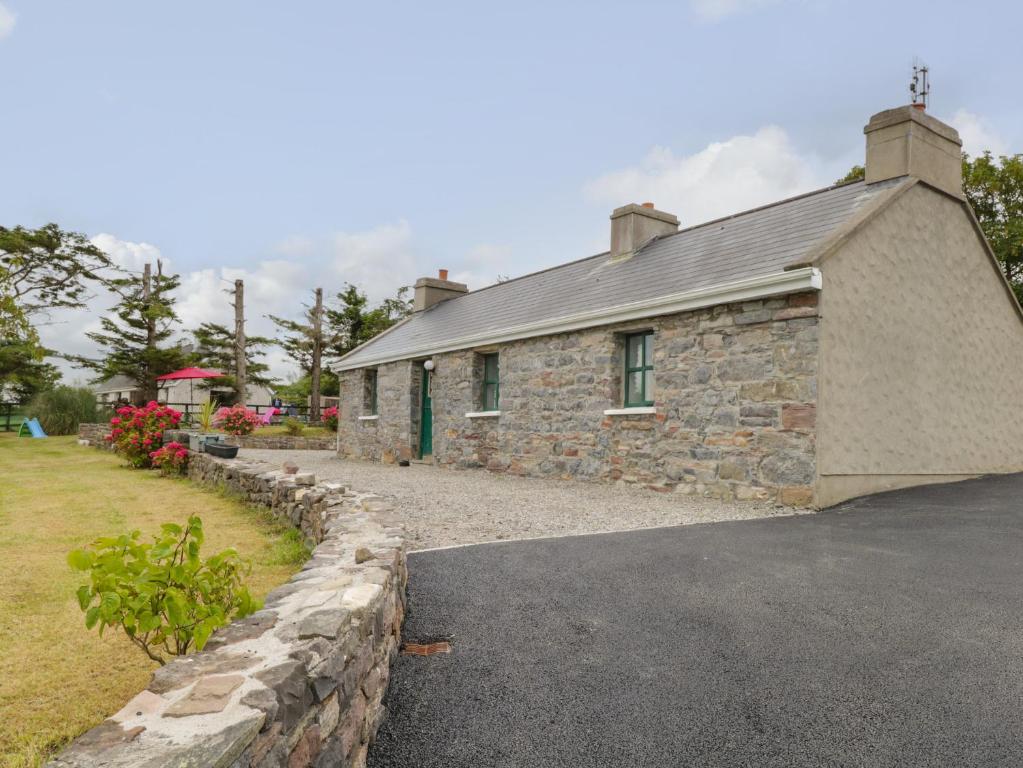a stone building with a stone wall next to a driveway at Toms Cottage in Westport